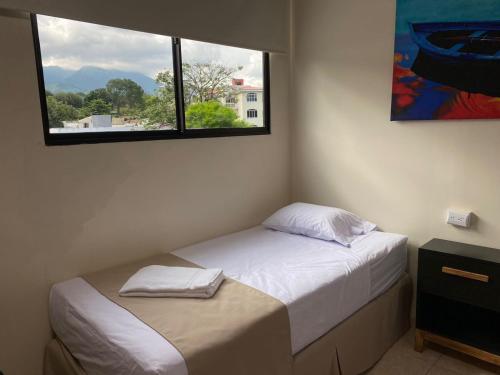 a small bedroom with a bed and a window at Hotel La Capilla - Suites & Apartments San Benito in San Salvador