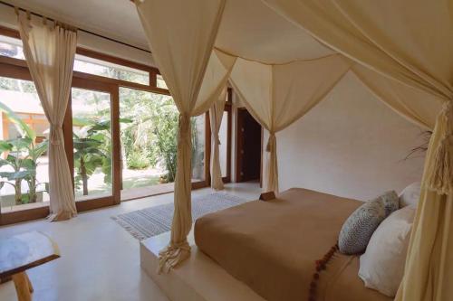 a bedroom with a canopy bed with a large window at Villa Sanah in Tulum