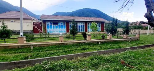 a house in a field with a wooden fence at Alp Hotel in Qax