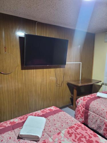 a hotel room with two beds and a flat screen tv at Hostal Balmaceda in Punta Arenas
