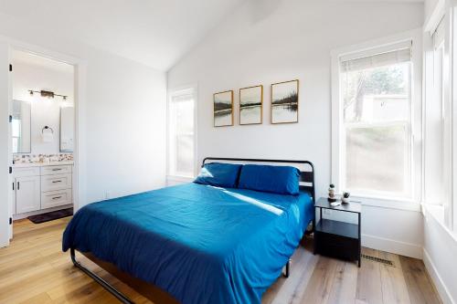 a white bedroom with a blue bed and a kitchen at Cozy in Cascade in Cascade