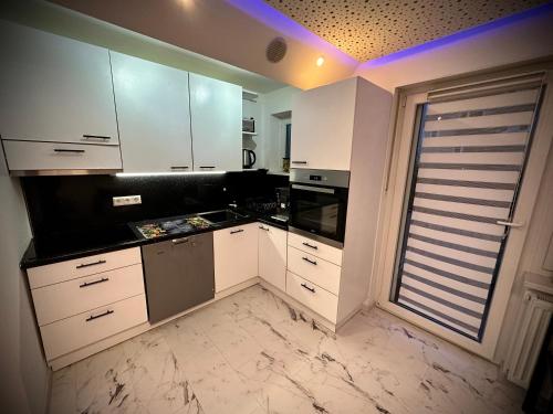 a kitchen with white cabinets and a large window at DeLuxe - Apartment ' Andrei 2 ' - Neu in Neuburg an der Donau mit Klimaanlage in Neuburg an der Donau