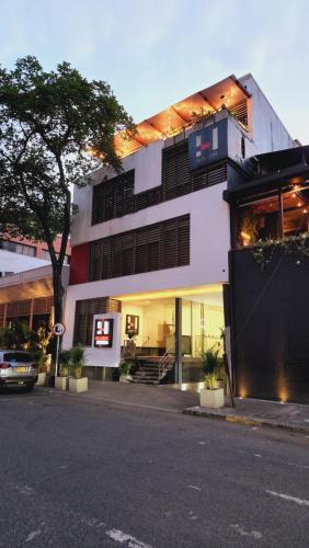 a white building with a tree in front of it at Hotel Austral Suites in Cali