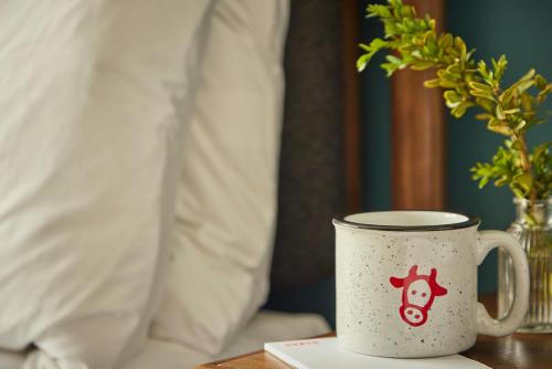 a coffee cup sitting on a table next to a bed at The Junto Hotel in Columbus