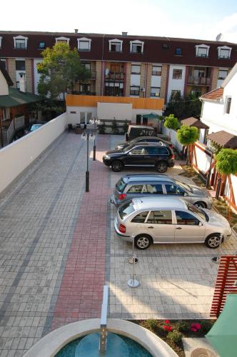 two cars parked in a parking lot in front of a building at Garni Boutique Hotel Arta in Novi Sad