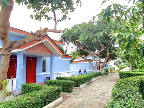 a blue house with a red door and trees at SCARLET SAILS BUNGALOW in Koh Rong Island