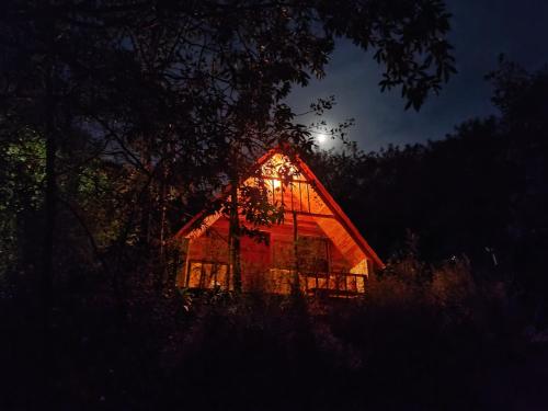 a barn lit up at night with the moon behind it at Chalé do Mirante do Itacolomi in Ouro Preto
