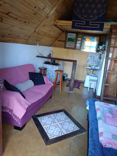 a living room with a purple couch and a table at Chalé do Mirante do Itacolomi in Ouro Preto