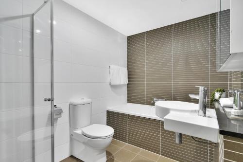 a bathroom with a toilet and a sink and a shower at Corporate Apartment North Sydney MIL2251306 in Sydney