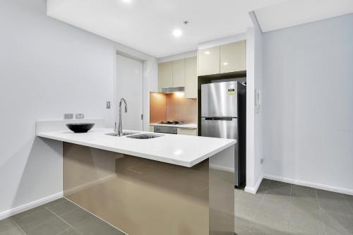 a white kitchen with a sink and a refrigerator at Corporate Apartment North Sydney MIL2251306 in Sydney