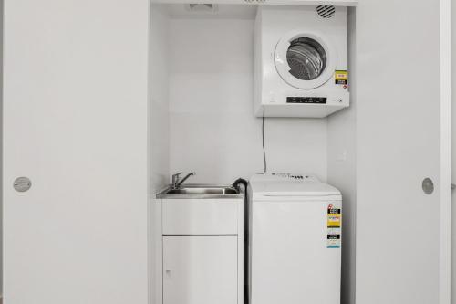 a small kitchen with a microwave above a refrigerator at North Sydney Corporate Apartment MIL2251106 in Sydney