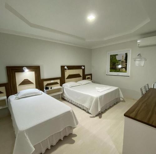 a hotel room with two beds and a counter at Grande Hotel in Paranavaí