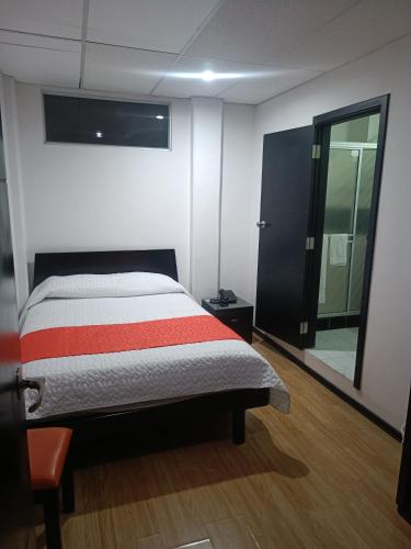 Un dormitorio con una cama con una raya roja. en Hotel Bariloche Confort, en Pasto