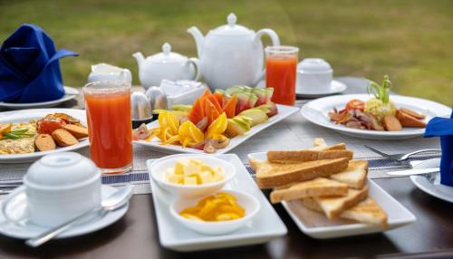 una tavola con piatti di cibo e brocche di succo di Jeans Holiday Resort a Kandy