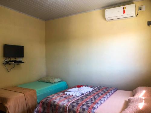 Habitación pequeña con 2 camas y TV. en Pousada Areias de Amaro, en Santo Amaro