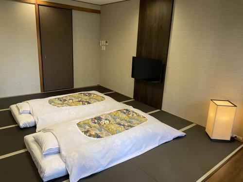 two beds in a hotel room with a tv at Gion Shinmonso in Kyoto