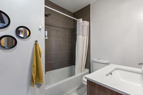 a bathroom with a tub and a sink and a toilet at Pristine Townhouse With Rooftop Deck Near Canton! in Baltimore