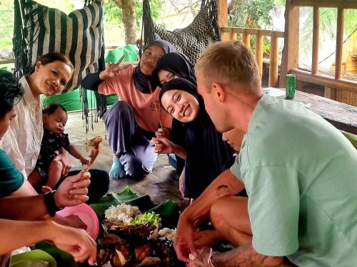 a group of people sitting around a table eating food at Tetebatu Hostel in Tetebatu