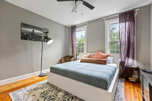 een slaapkamer met een bed, een lamp en ramen bij Pristine Townhouse With Rooftop Deck Near Canton! in Baltimore