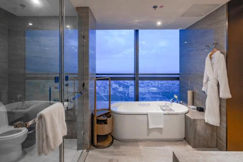 a bathroom with a tub and a shower with a window at The Westin Zhongshan Guzhen in Zhongshan