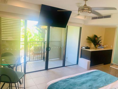 Schlafzimmer mit einem Bett und einem Tisch sowie einem Balkon in der Unterkunft Tropical Retreat - Poolside Swimout - Ground Floor - Sea Temple Resort & Spa Port Douglas in Port Douglas