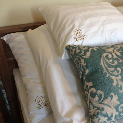 a bed with white pillows and a green pillow at Vass-Villa Vendégház in Szekszárd