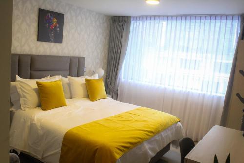 a bedroom with a bed with yellow sheets and a window at BLISS BOUTIQUE HOTEL BOGOTA in Bogotá