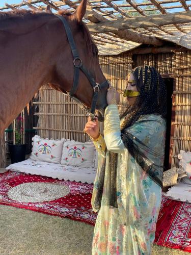 a woman is standing next to a horse at اسطبلات أساور للفروسية Asawer Equestrian Stables 