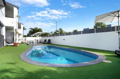 una piscina en un patio con césped verde en Noosa Parade Holiday Inn, en Noosa Heads