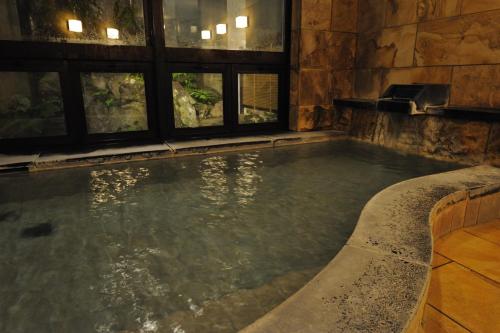 una gran piscina de agua en un edificio con ventanas en Hakuba Onsen Ryokan Shirouma-so en Hakuba