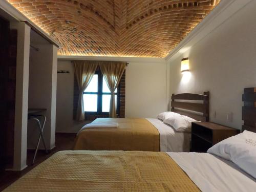 a bedroom with two beds and a ceiling with a window at Hotel Santa Irene in Cholula