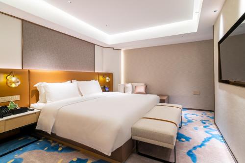 a bedroom with a large white bed and a television at Landmark International Hotel in Guangzhou