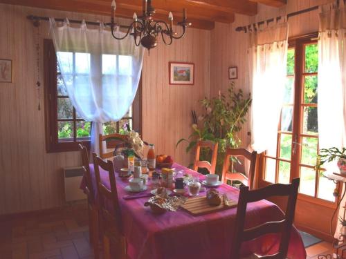 une salle à manger avec une table et un tissu de table rose dans l'établissement Séjour bucolique en Sologne avec chambres confortables dans maison accueillante - FR-1-590-359, à Vannes-sur-Cosson