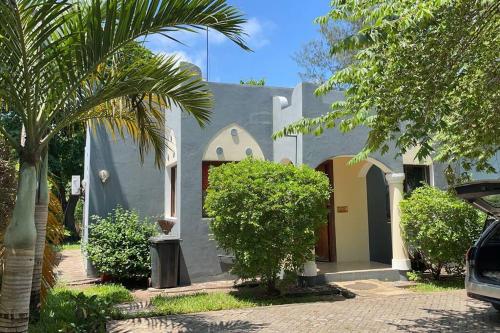 a blue and white house with a palm tree at Romantic Mediterranean beach house in Dar es Salaam