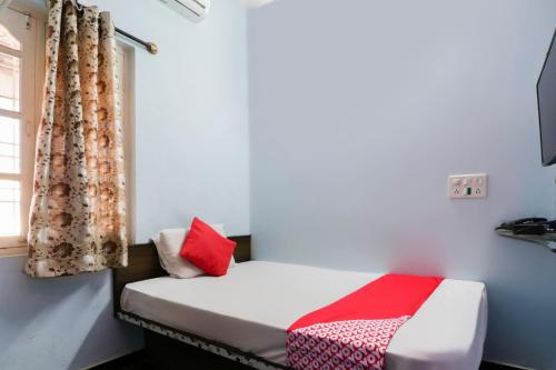 a small room with a bed and a window at Flagship Shree Raksha Comforts in Devanhalli