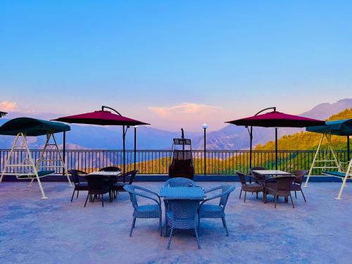 a patio with tables and chairs and umbrellas at Hotel Pine Rock Mountain View, Mussoorie in Mussoorie