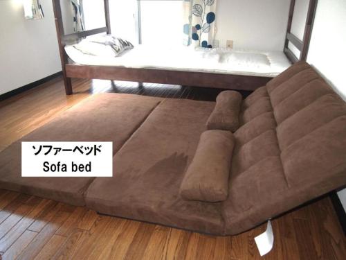 - un canapé brun dans le salon avec un lit dans l'établissement Cocostay Jarudan ココステイ ジャルダン, à Hiroshima