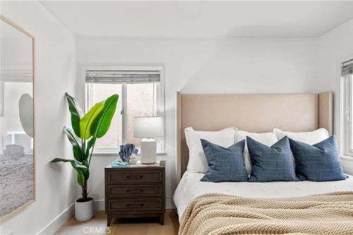 a bedroom with a bed with blue pillows and a plant at Amazing location! Luxurious beach cottage.Ocean views in Manhattan Beach