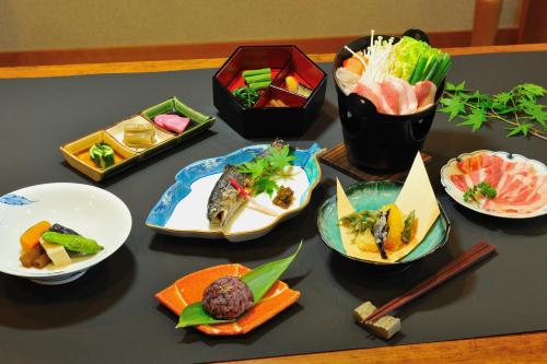 einen Tisch mit Teller mit Lebensmitteln und Essstäbchen in der Unterkunft Hakuba Onsen Ryokan Shirouma-so in Hakuba