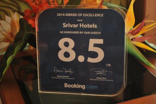 a digital alarm clock on a table with flowers at Srivar Hotels in Guruvāyūr