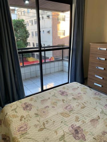 ガラパリにあるSolar de Bruna - Apartamento com 2 Qts - 1 Suíte - Garagem coberta - Wi-Fi - Netflix - Acomoda 6 pessoas a 70 metros da praiaのベッドルーム1室(ベッド1台、大きな窓付)