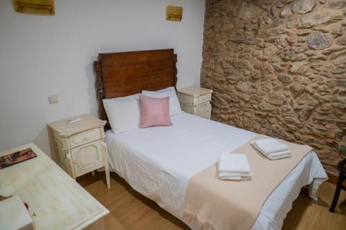 - une chambre avec un lit et un mur en pierre dans l'établissement Casa da Rua histórica, Cabeceiras de Basto T3, à Cabeceiras de Basto