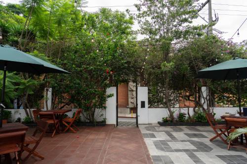 eine Terrasse mit Tischen, Sonnenschirmen und Bäumen in der Unterkunft RIO HOSTEL in Guatemala
