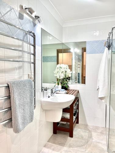 a white bathroom with a sink and a mirror at SilverWaters Waterfront Accommodation Lake Macquarie in Morisset East