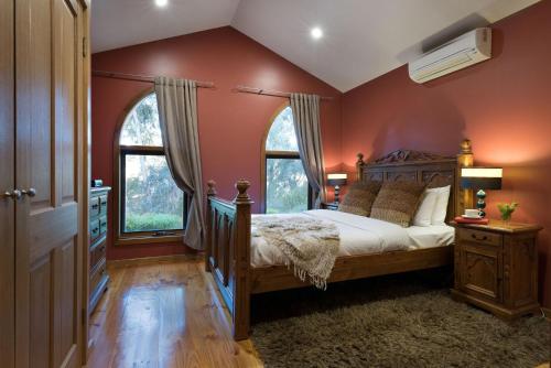 ein Schlafzimmer mit einem großen Bett und zwei Fenstern in der Unterkunft Abbotts Rest in Hepburn Springs