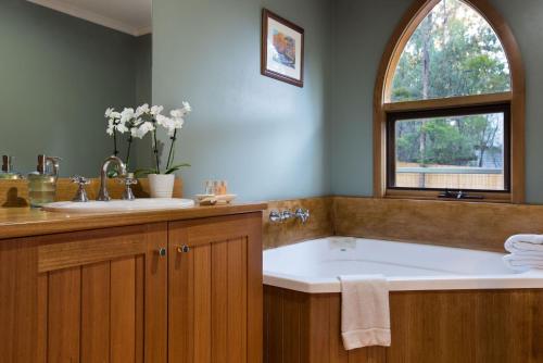 ein Bad mit einer Badewanne, einem Waschbecken und einem Fenster in der Unterkunft Abbotts Rest in Hepburn Springs