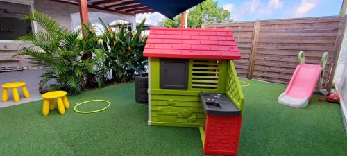 a small toy house on the grass in a backyard at Kukumi's House avec Piscine in Sainte-Anne