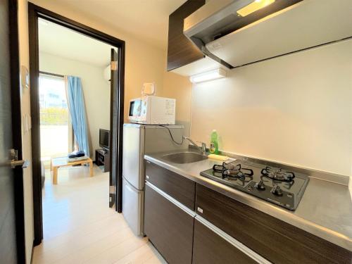 a kitchen with a sink and a stove and a microwave at Credo Maison Kamakura - Vacation STAY 10394 in Kamakura