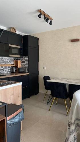 une cuisine avec des armoires noires, une table et des chaises dans l'établissement Luxueux appartement centre, à Antibes