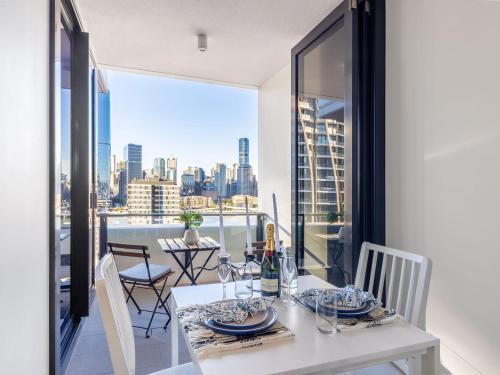 a white dining room with a view of the city at Explore BNE from our Cute 1-Bed Apartment in South Brisbane in Brisbane